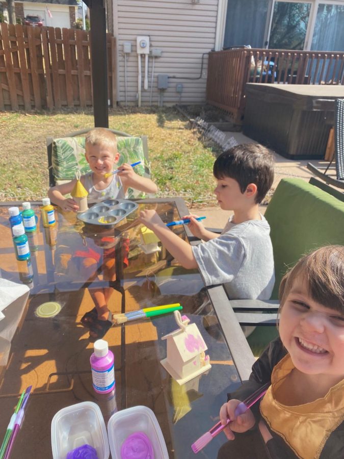 ernathy’s grandchildren sitting at a table, doing fun activities such as painting. They’re in Abernathy’s backyard.