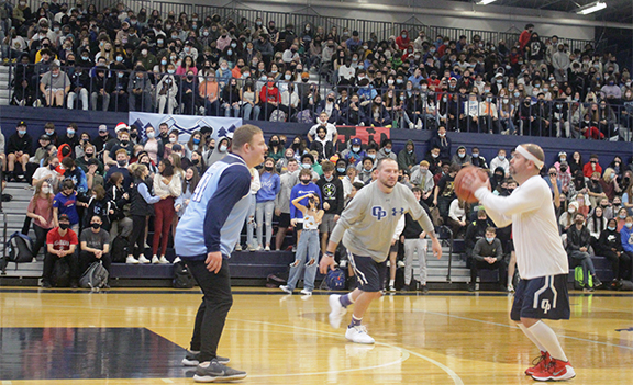 Alumnus coach Ross Sharp defends the basket during the Winter Assembly in December 2021. Teachers played teachers in a short half-court game.