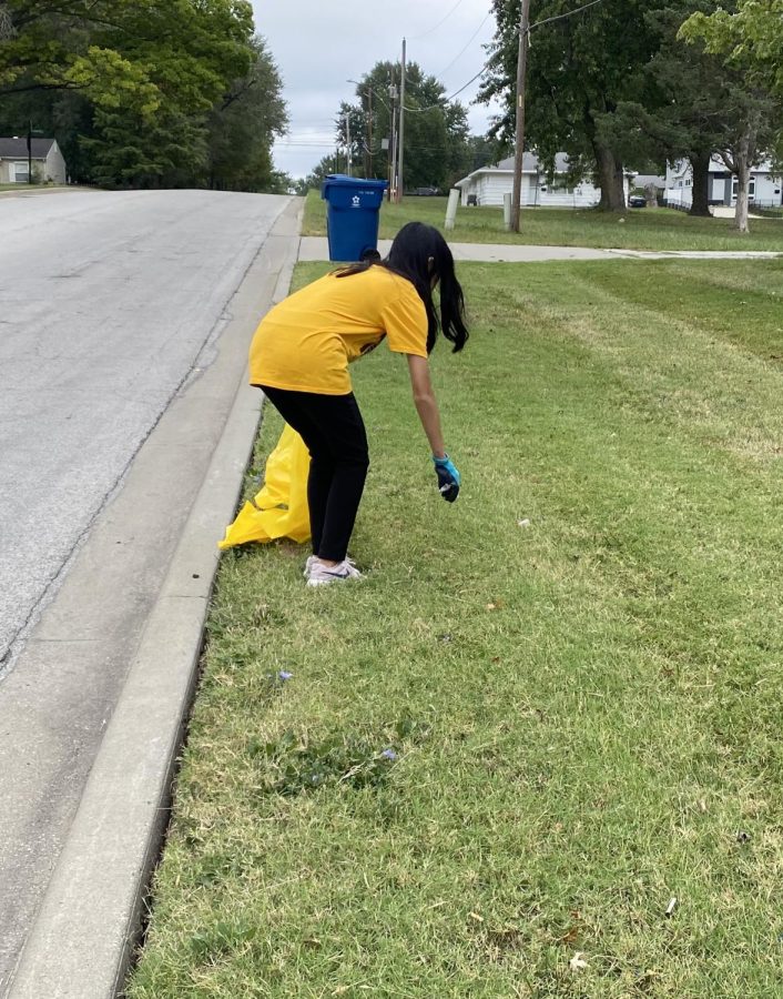 Junior Chelsea Trieu picks up trash in a neighborhood alongside the streets of Gladstone.