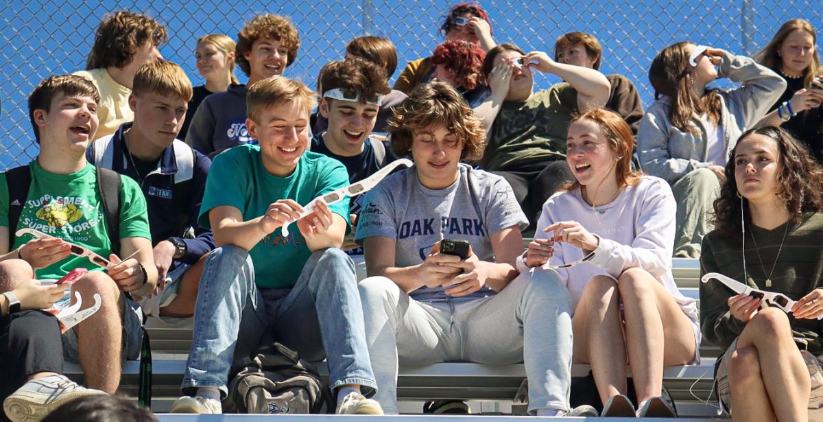 Warm smiles flow amongst the faces of juniors Ahren Wettlaufer, Bryson Netherton, Truman Camarda, Jacob Eischen, Ben Place, and Clara Timmons while they sit on the bleachers and chat.