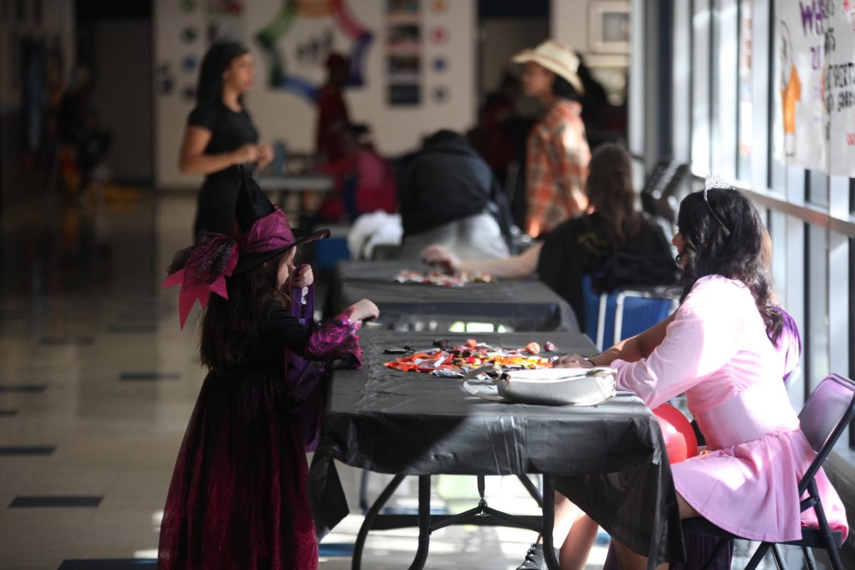 A tiny witch takes candy from a Cheer Trunk or Treat table. The event ran from 1 to 4 p.m. Sunday, Oct. 27, in the main courtyard and surrounding hallways.