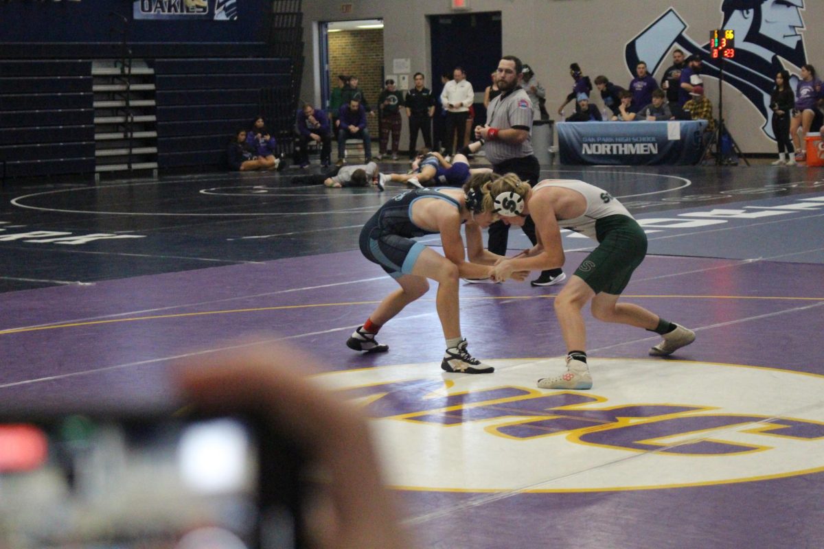 Freshman Gage Eischen warms up with freshman William Sprouse. Each wrestler warms up with jogging, sprinting and hand fighting to make sure they are prepared for their match. “I focus on breathing before a match because it helps me stay calm, and warming up before helps my body get ready and warmed for the match,” Eischen said.