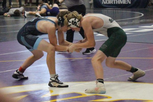 Freshman Gage Eischen warms up with freshman William Sprouse. Each wrestler warms up with jogging, sprinting and hand fighting to make sure they are prepared for their match. “I focus on breathing before a match because it helps me stay calm, and warming up before helps my body get ready and warmed for the match,” Eischen said.