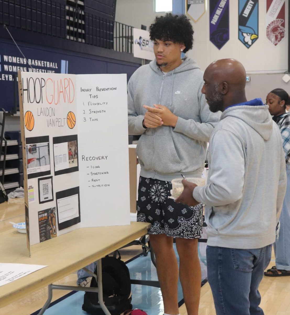 Senior Landon VanPelt presents his poster board on "hoop guard" to special education teacher Martrez Taylor. VanPelt said how young basketball players can prevent injuries. He really liked this project, "It felt good to you know talk about it."