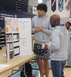 Senior Landon VanPelt presents his poster board on "hoop guard" to special education teacher Martrez Taylor. VanPelt said how young basketball players can prevent injuries. He really liked this project, "It felt good to you know talk about it."
